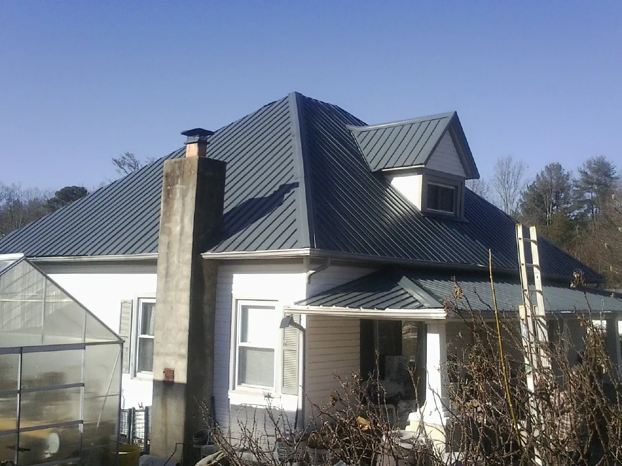 Dark blue standing seam metal roof on a white farmhouse with dormer — Slate & Tile Roof Repair by Roofing Brothers in Bonduel