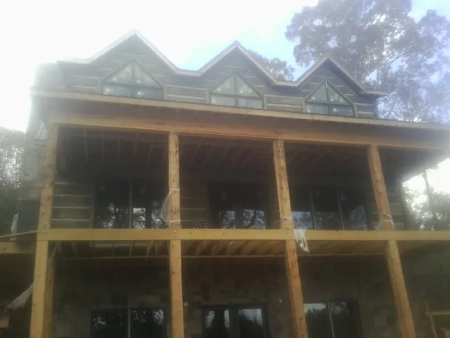 Dormers and porch framing on a large log home under construction — Roof Coating work by our crew in Bonduel