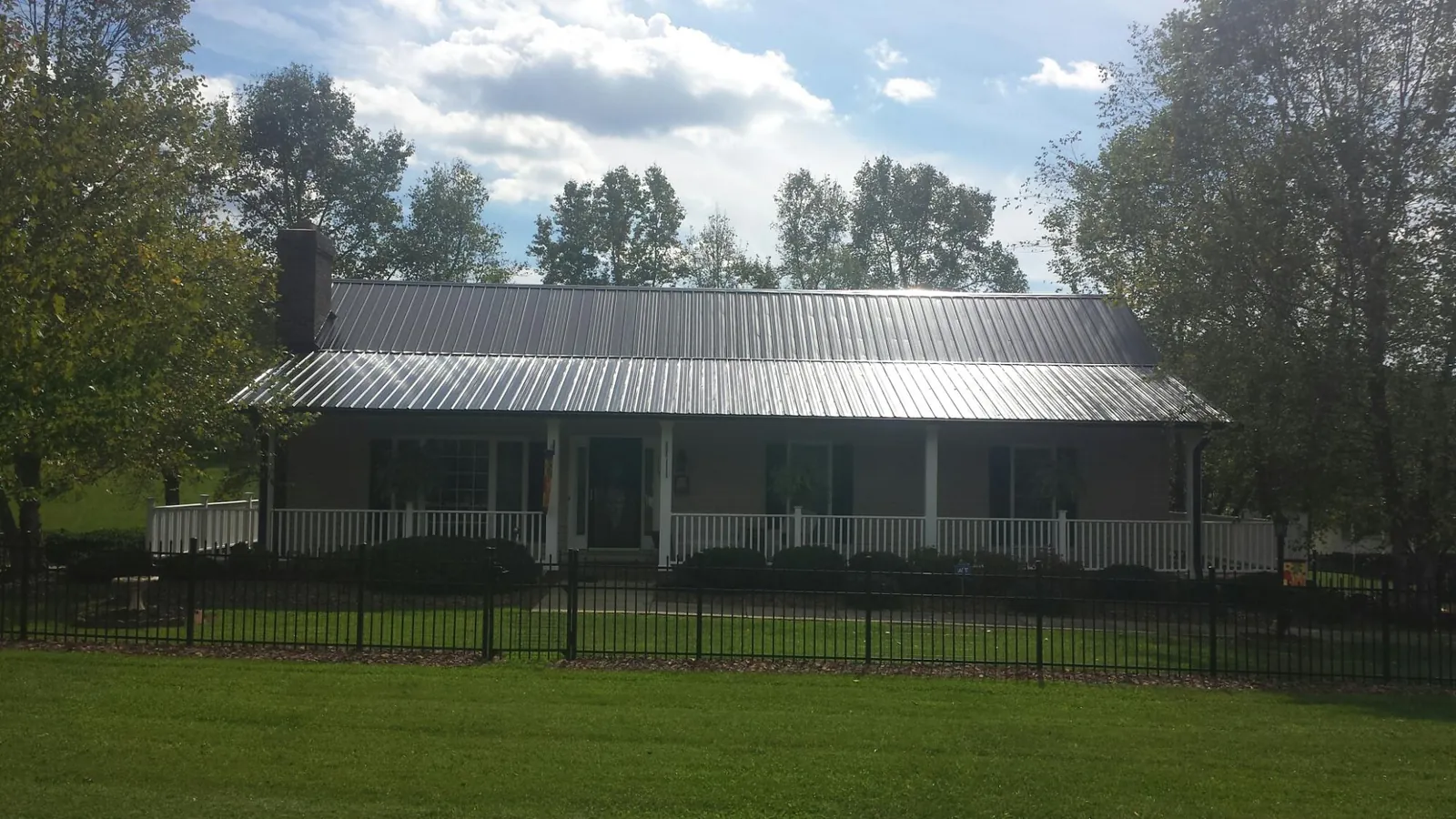 Gray metal roof on a brick ranch with a full width front porch — Gutter Guard Installation work by our crew in Bonduel