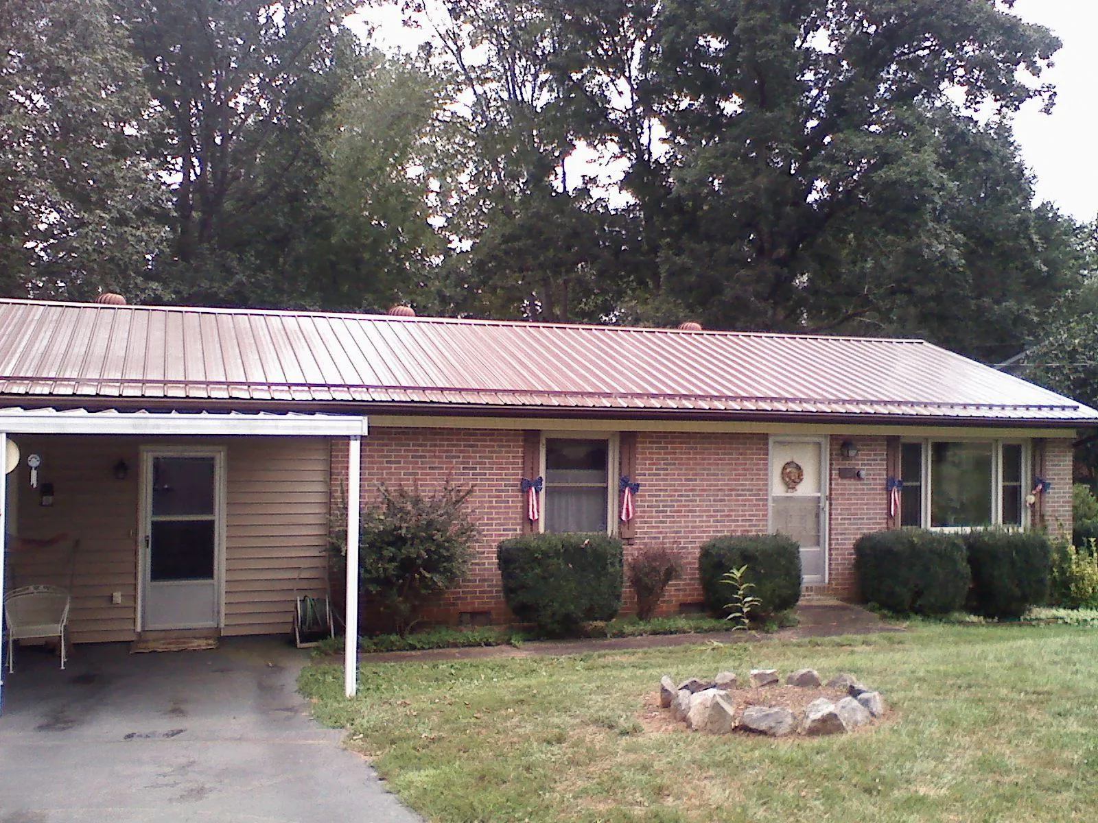 Bronze metal roof and carport on a brick ranch home — Roof Repair work by our crew in Bonduel